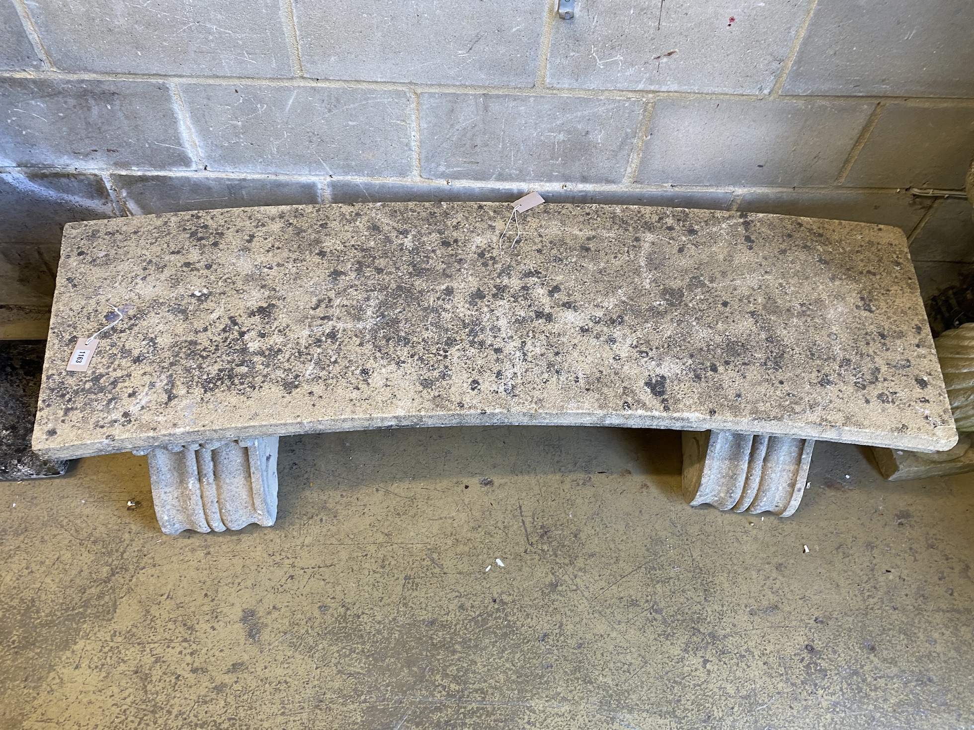 A reconstituted stone curved garden bench, width 173cm, depth 54cm, height 45cm